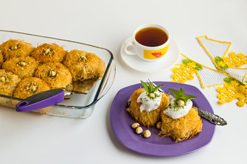 Traditional Turkish Crispy Dessert  Cup Kadayif,in glass oven container on white with tea and nuts.