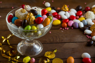 Colorful Turkish almond candies in a glass bowl on wooden table with chocolates.The Sugar Feast after Ramadan.