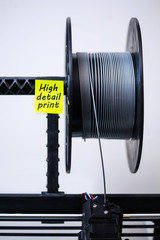A 3d printer head with loaded filament and a spool of PLA material for high detail 3d printing.