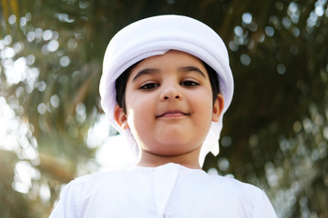 Arab Emirati boy student portrait wearing traditional middle eastern gulf kandora  ready to go to...