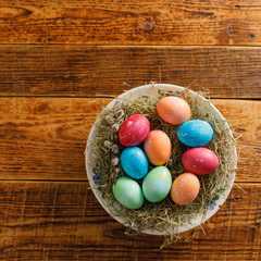 Obraz na płótnie Canvas Still life of easter eggs in a bird's nest on a wooden background. Rustic. Easter celebration concept. Copy space. Flat lay. Square.