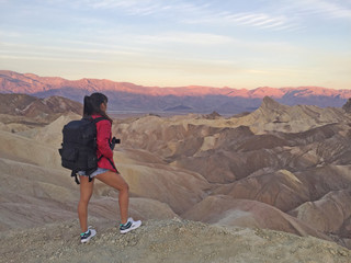 Fototapeta premium Woman watching beautiful sunrise from Zabriskie Point at Death Valley National Park in California USA