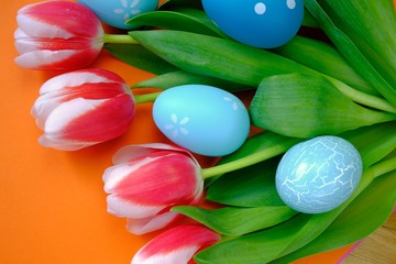 Easter holiday.  blue easter eggs in tulip flowers on a bright orange background.Spring holiday background