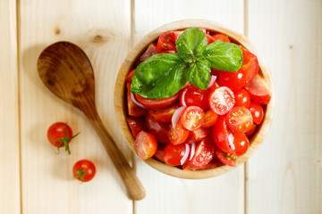 red cherry tomato and basil leaf on wooden bowl on wooden background