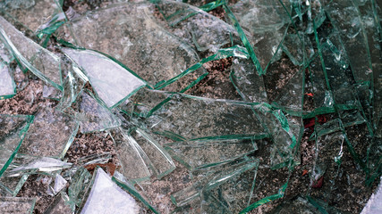 The glass is broken into pieces on the cement floor.