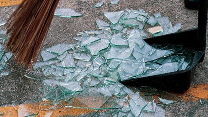 Broken glass on the floor with a broom and dustpan.