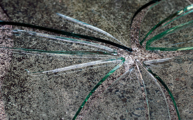 The glass is broken into pieces on the cement floor.