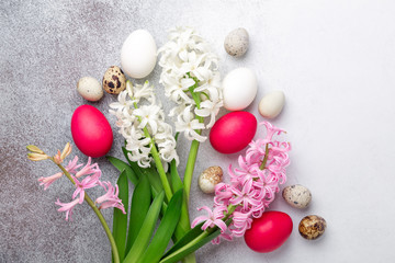 Fototapeta na wymiar Bright Easter composition with quail, easter eggs, pink and white hyacinth on stone background. Flat lay, top view. Easter concept