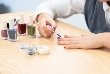 Obraz na płótnie Canvas A young woman paints her own nail polish at home