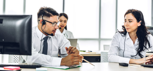 Group of happy call center smiling business operator customer support consult team phone services agen working and talking with wireless headset microphone on desktop computer at call center office