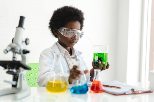 African american cute little boy student child learning research and doing a chemical experiment while making analyzing and mixing liquid in glass at science class on the table.Education and science - Powered by Adobe
