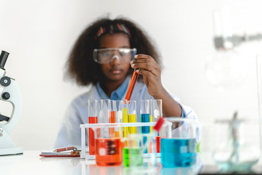 African american cute little girl student child learning research and doing a chemical experiment while making analyzing and mixing liquid in glass at science class on the table.Education and science 