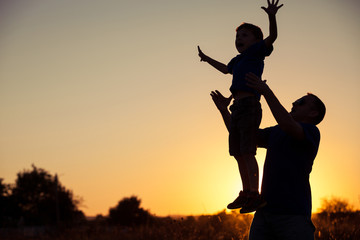 Father and son playing in the park at the sunset time.