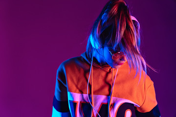 Teen girl wear headphones listen music, dancing standing at purple background.