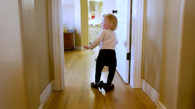 Adorable toddler tries on her mother's high heel shoes and stomps around the house pretending to be a grownup