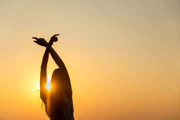 Young woman relaxing in summer sunset sky outdoor,breathing fresh air raising arms.