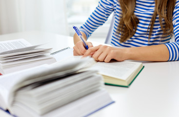 education, school and learning concept - close up of student girl copying text from textbook to exercise book at home