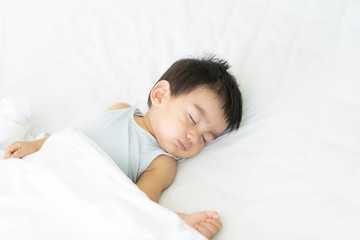 A cute little asian baby boy is peaceful sleeping on the bed in the bedroom with happiness moment, concept of first year growth and development of the child.