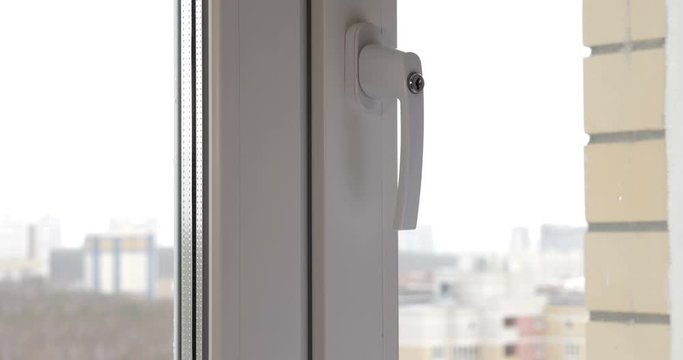 A man closing a window with a key