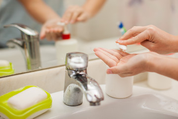 Woman antibacterial liquid soap for hands in bathroom. People and healthcare concept.