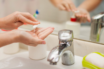 Woman antibacterial liquid soap for hands in bathroom. People and healthcare concept.
