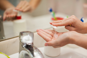 Obraz na płótnie Canvas Woman antibacterial liquid soap for hands in bathroom. People and healthcare concept.