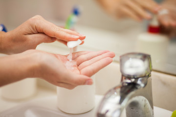 Woman antibacterial liquid soap for hands in bathroom. People and healthcare concept.