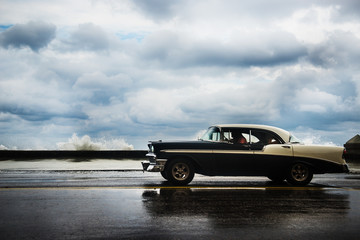 1950's car driving along the Malecon on a cloudy day, Havana, Cuba