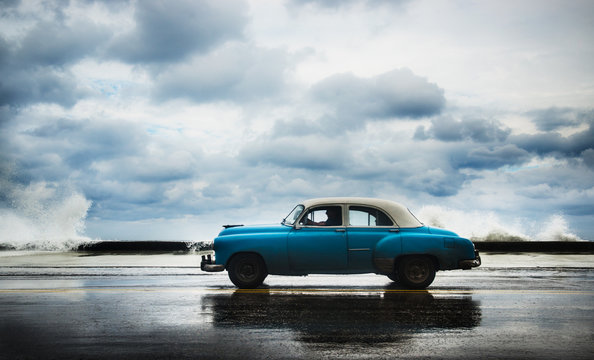 1950's car driving along the Malecon on a cloudy day, Havana, Cuba