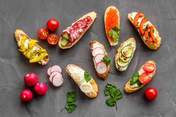Sandwiches - set with vegetables, caviar, salami - on grey background top-down