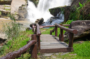 Brown wooden bridge to beautiful white waterfall