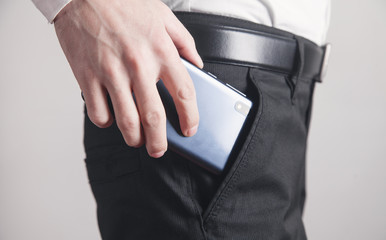 Man putting smartphone in pocket of trousers.