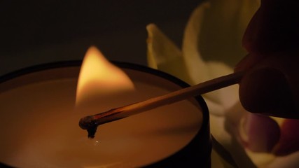 Light candle by match, close up of burning scented soy candle. Aromatherapy, massage, spa concept