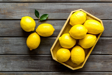 Ripe lemons in tray on dark wooden backgroud top-down
