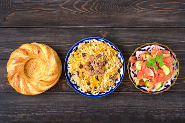 National Uzbek pilaf with meat, achichuk salad of tomato, cucumber, onion in plate with traditional...