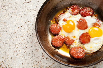 Copper pan with fried egg and sausage