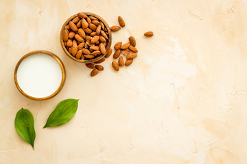 Fototapeta na wymiar Almond milk near nuts on beige background top-down copy space