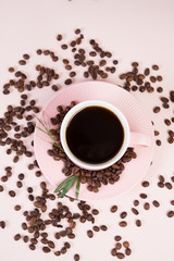 A Cup of strong black coffee surrounded by coffee beans in pastel, monochrome colors