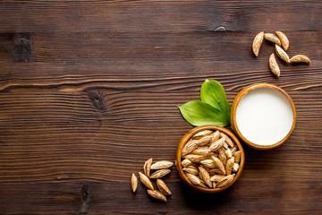 Alternative milk made from almond. Drink near unpeeled on dark wooden table top-down copy space