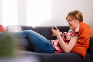 Obraz premium Texting with smartphone: young attractive girl is texting with her boyfriend