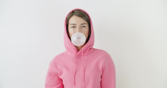 girl dressed in pink hoodie blowing bubblegum