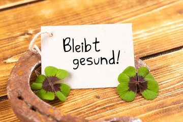 horseshoe with green shamrock and german text bleibt gesund, in english stay healthy