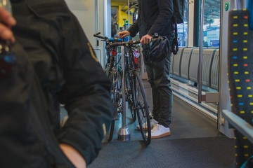 Unknown commuter with a bicycle inside a train or railway coach on his daily commute. Person traveling with a bicycle on a train.