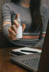 Work space with hand sanitizer antibacterial in hands, laptop, notebook, pen, phone. view on dark wood table and woman background. protection against bacteria. remote work covid-19, coronavirus