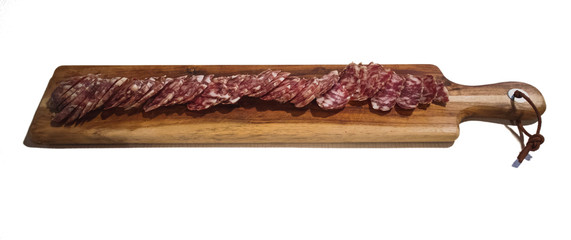 Home made salami in slices served on a wooden slicing board isolated on white.
