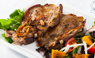 Fried pork meat chops with salad of fried orange and vegetables