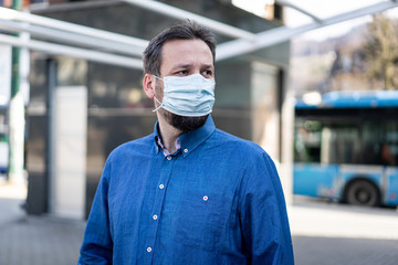 Fototapeta na wymiar Adult man on city street with mask against Coronavirus
