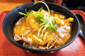 Japanese curry rice with beef in a black bowl on table with nature light through the window.