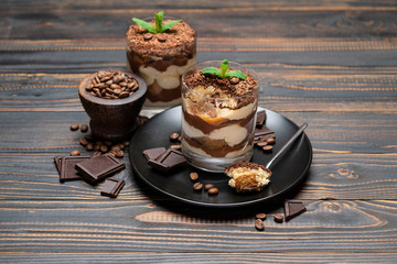 Classic tiramisu dessert in a glass cup on wooden background