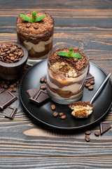 Classic tiramisu dessert in a glass cup on wooden background